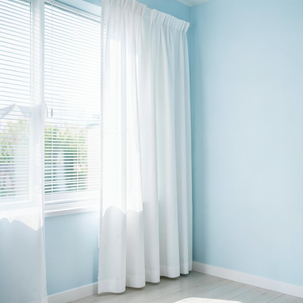 Cortinas e persianas claras higienizadas em ambiente iluminado
